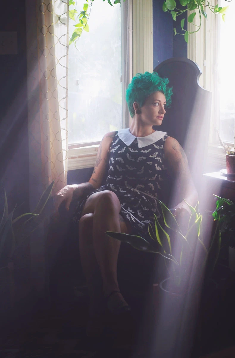 image of Sami, sitting in a corner surrounded by windows and plants.
